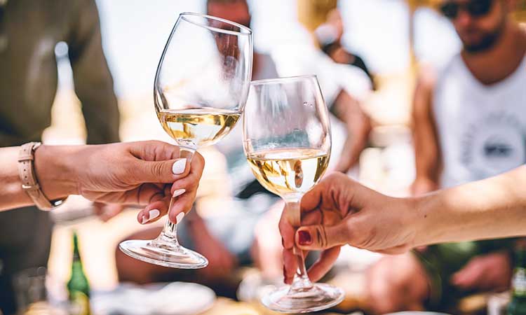 white wine with friends, two female hands holding a glass with white wine